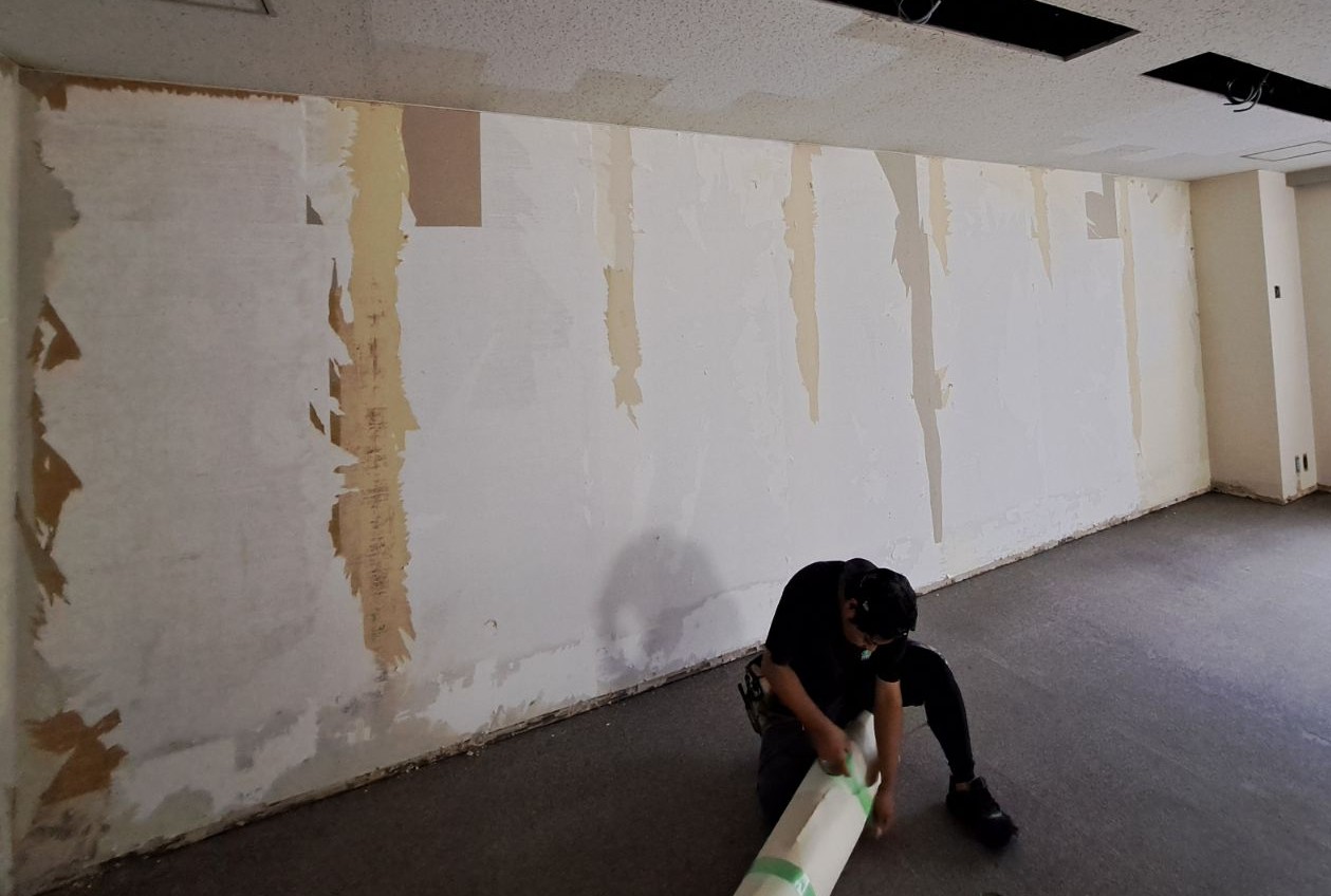 既存クロスを撤去した壁面で作業する施工現場